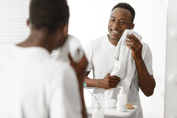 Siyah adam banyoda tıraş olduktan sonra yüzünü havluyla siliyor. — Stok fotoğraf