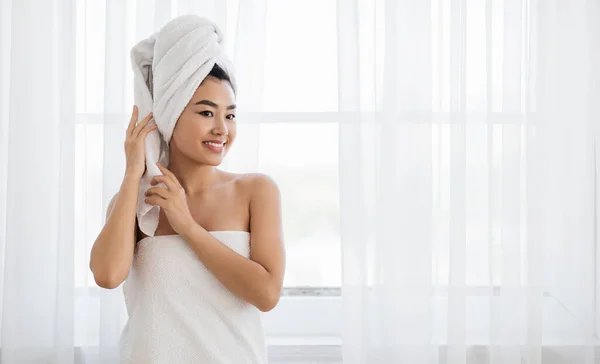 Mulher asiática envolto em toalha de pé ao lado da janela — Fotografia de Stock