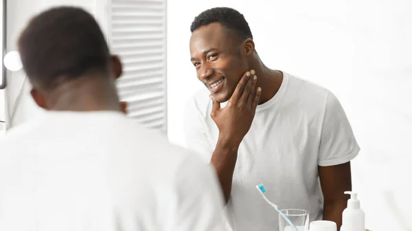 Afroamericano uomo toccare faccia dopo rasatura in piedi in bagno — Foto Stock