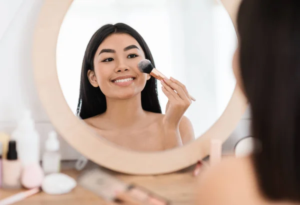 Feliz bonita mulher asiática aplicando blush em seu rosto — Fotografia de Stock