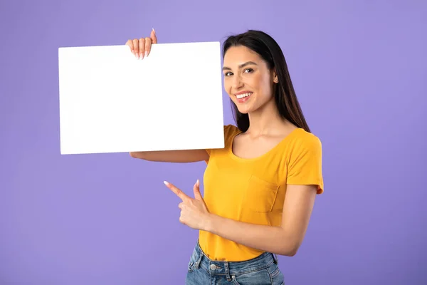 Gelukkige jonge dame wijzen naar wit papier boord — Stockfoto