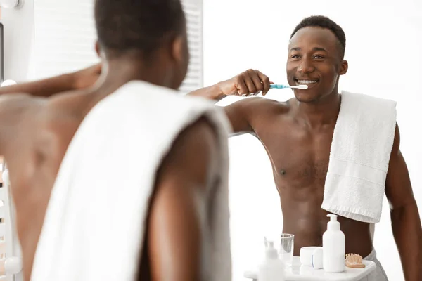 バスルームでミラーの近くに立ってアフリカ人男性ブラッシングクリーニング歯 — ストック写真