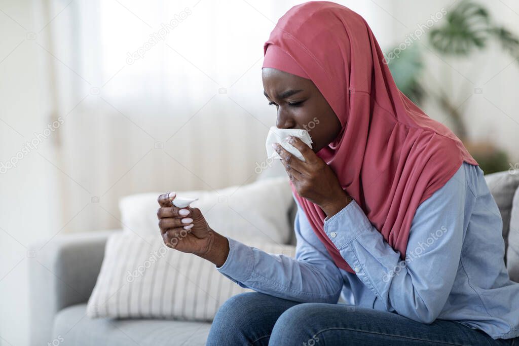 Ill Black Muslim Lady Checking Temperature And Blowing Nose At Home