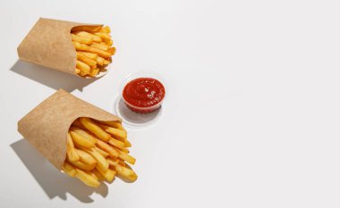 Müşteri siparişi ve fast food teslimatı. Eko karton paketlerde patates kızartması ve plastik kabın içinde ketçap, beyaz arka planda izole edilmiş gölgeli.