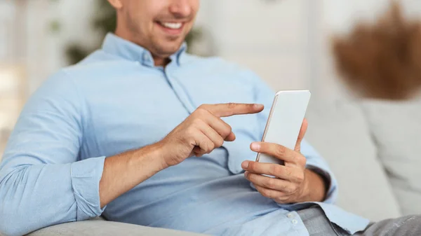 Closeup of smiling guy using smartphone at home — Stock Photo, Image
