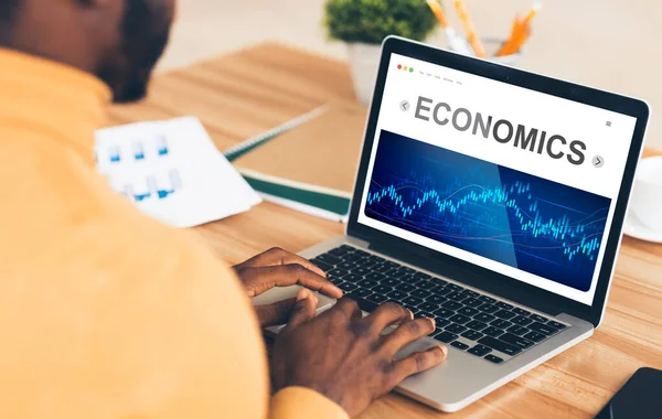 Uomo d'affari africano che lavora al computer portatile che analizza i grafici di economia nell'ufficio — Foto Stock