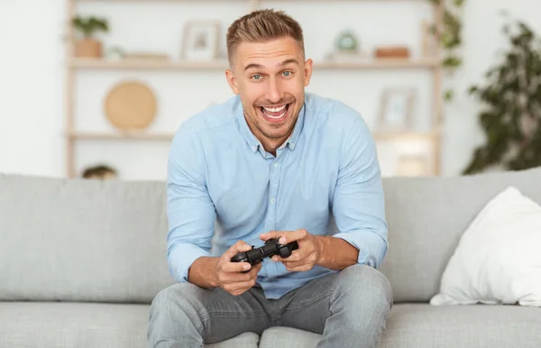 Junger Kerl sitzt auf Couch und spielt Videospiele — Stockfoto