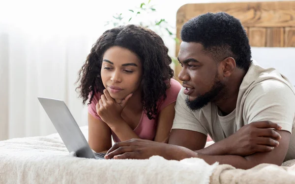 Pensive αφρικανικό ζευγάρι ψάχνει για κάτι σε απευθείας σύνδεση, χρησιμοποιώντας το laptop — Φωτογραφία Αρχείου
