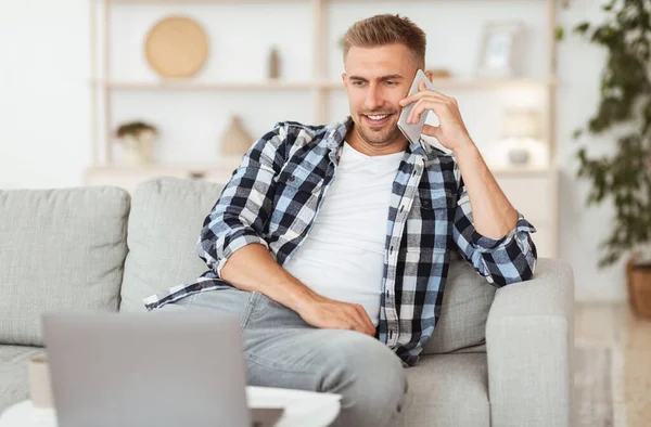 Sorrindo cara usando pc falando no telefone — Fotografia de Stock