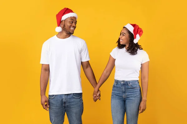 Afro-Amerikaans paar in Santa hoeden Handen vasthouden, Studio schot — Stockfoto