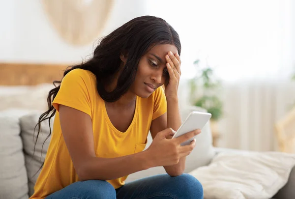 Ongelukkig Afro-Amerikaanse dame kijkt naar haar smartphone met walging binnen, kopieer ruimte — Stockfoto