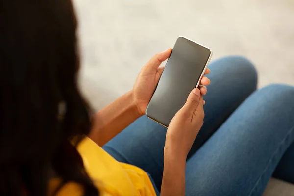 Afroamerikanerin hält Smartphone mit leerem Bildschirm auf Sofa zu Hause, Mockup für mobiles App-Design — Stockfoto