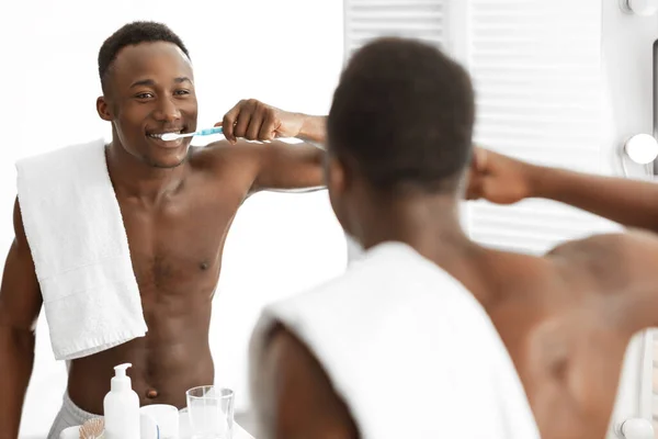 Afroamericano chico limpieza dientes con cepillo de dientes de pie en cuarto de baño — Foto de Stock