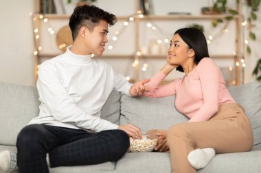 Japon çift sohbetin tadını çıkarıyor evde oturmuş patlamış mısır yiyor.