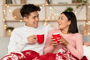 Neşeli Çinli çift evde Noel arifesini kutlamak için kahve içiyorlar.