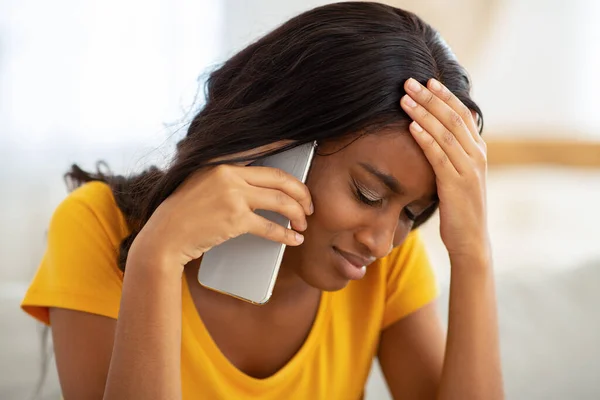 Несчастная черная женщина говорит по мобильному телефону дома — стоковое фото
