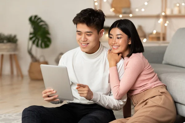 Casal coreano feliz usando computador tablet sentado em casa — Fotografia de Stock