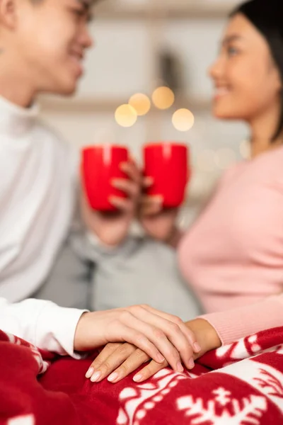 Japanisches Paar hält sich an Weihnachten zu Hause beim Kaffeetrinken die Hände — Stockfoto