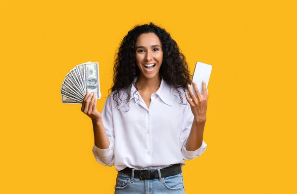 Αντίληψη Cashback. Ενθουσιασμένη νεαρή γυναίκα κρατώντας Smartphone και Δολάριο μετρητά — Φωτογραφία Αρχείου