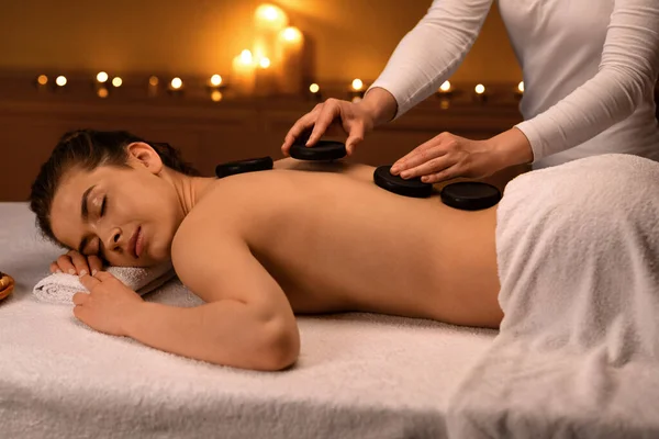 Entspannte Dame erhält Hot-Stone-Massage im modernen Wellnessbereich — Stockfoto