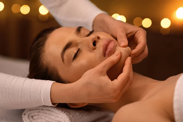 Mulher relaxada recebendo massagem facial de cura no spa — Fotografia de Stock