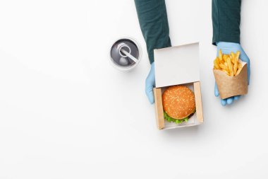Fast food restoranında sipariş verin. Lastik eldivenli garson, karton kutuda burger, kese kağıdında patates kızartması, kola, buz ve samanla birlikte cam verir.