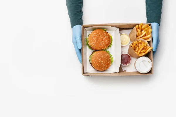 Comida rápida de moda y almuerzo para dos. Camarero da caja con hamburguesa y hamburguesa con queso, papas fritas en paquetes de papel, con salsa y ketchup, y café en taza para el cliente — Foto de Stock