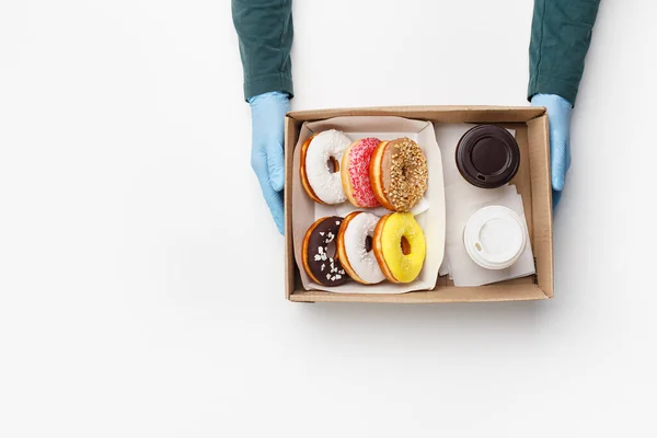 Caffè con dolci per due da asporto durante l'epidemia di Baccalà. Cameriere in guanti di gomma dà scatola di ciambelle con smalto e briciole e tazze di caffè — Foto Stock