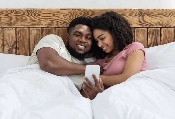 Loving black couple watching photos together on smartphone — Stock Photo, Image