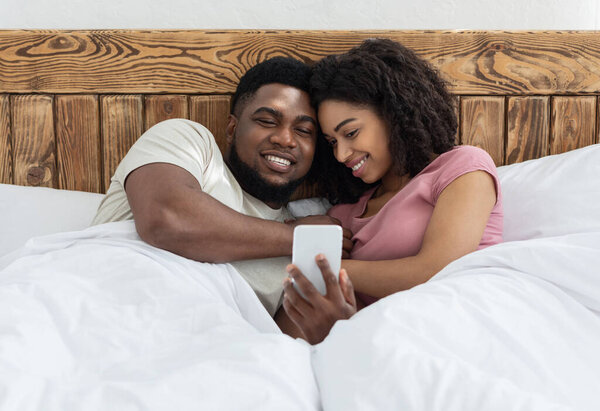 Loving black couple watching photos together on smartphone