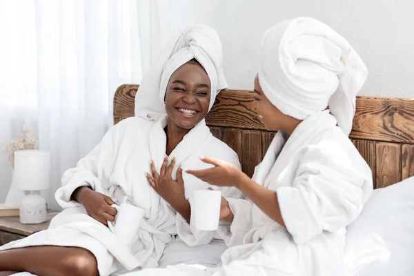 Twee lachende zwarte vrouwen die thuis koffie drinken — Stockfoto