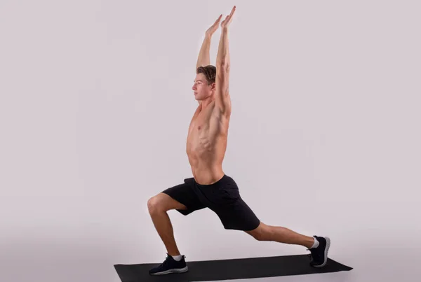 Hälsosam livsstil och välbefinnande. Flexibel ung kille som gör yoga eller pilates övningar på ljus studio bakgrund — Stockfoto