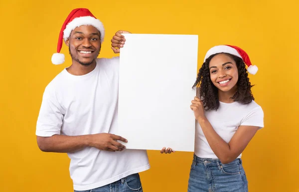 Африканська пара тримає порожній різдвяний плакат позує в студії — стокове фото