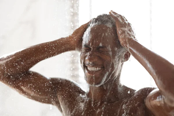 Homme noir se lavant la tête et le corps prenant douche dans la salle de bain — Photo