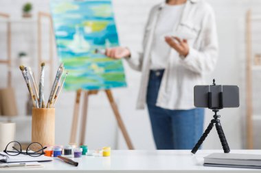 Çağdaş sanat, hobiler ve evde online ders. Akıllı telefon, boya ve fırçalara odaklan. Oturma odasındaki Afrikalı Amerikalı kadın ressamların resimlerine odaklan.