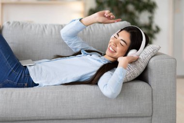 Boş zaman rahatla. Neşeli Koreli Kadın Evde Kulaklıkla Müzik Dinliyor