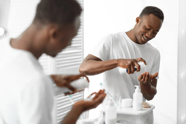 Afrikai férfi használ borotválkozás hab álló tükör közelében Fürdőszobában — Stock Fotó