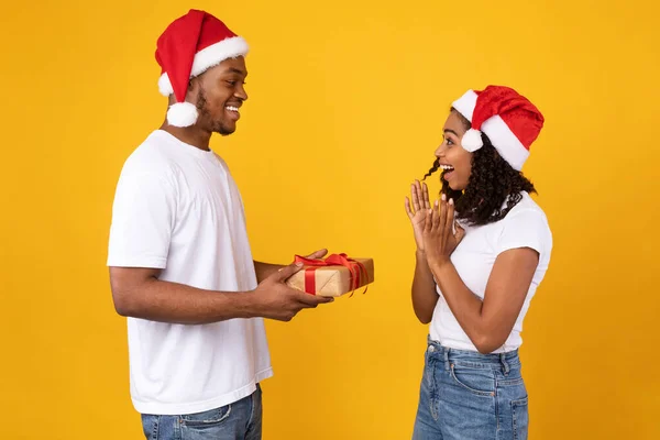 Afrikalı Koca Şaşırmış Eşe Noel Hediyesi Veriyor, Sarı Arkaplan — Stok fotoğraf