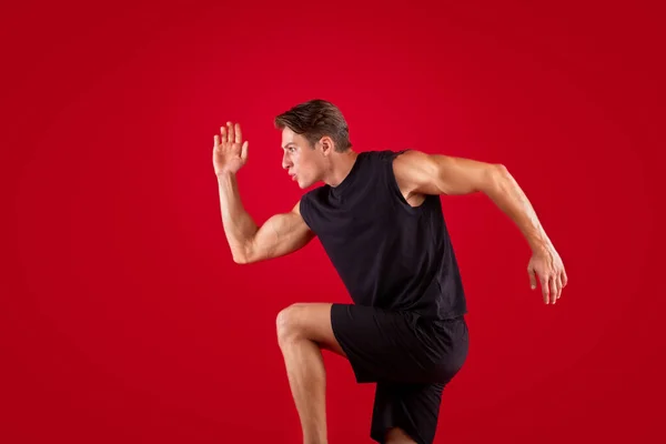 Portrait of focused young man running fast on red studio background — Stok Foto