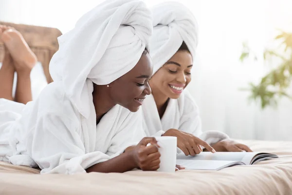 Senhoras negras alegres bebendo chá e ler revista — Fotografia de Stock
