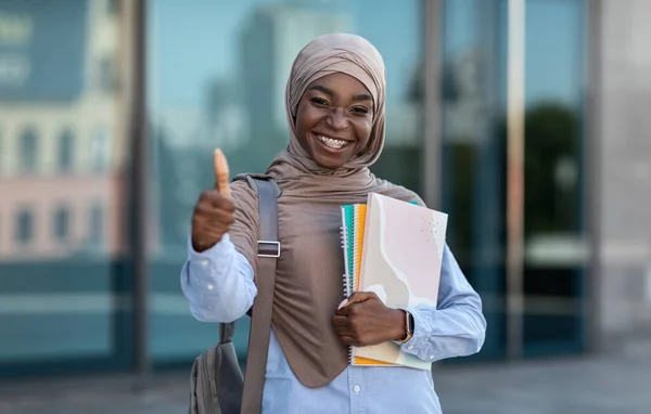 Tanulmányi programok iszlám diákoknak. Fekete muszlim nő pózol a szabadban, megjelenítve hüvelykujj fel — Stock Fotó