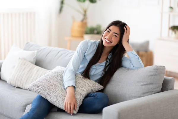 Retrato doméstico. Mujer coreana alegre posando en cómodo sofá en casa — Foto de Stock