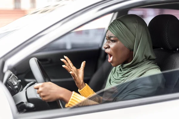 Verkeersstress. Boze zwarte moslim vrouw rijden auto en schreeuwen tegen iemand — Stockfoto