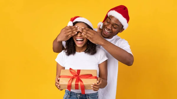 Esposo Felicitando a la Esposa en Navidad, Cubriendo sus ojos, Fondo Amarillo — Foto de Stock