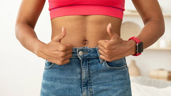 Mujer negra con vientre muscular plano Gesturing Thumbs-Up de pie en interiores — Foto de Stock