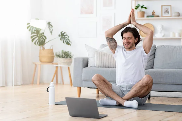 Щасливий хлопець практикує йогу перед ноутбуком — стокове фото