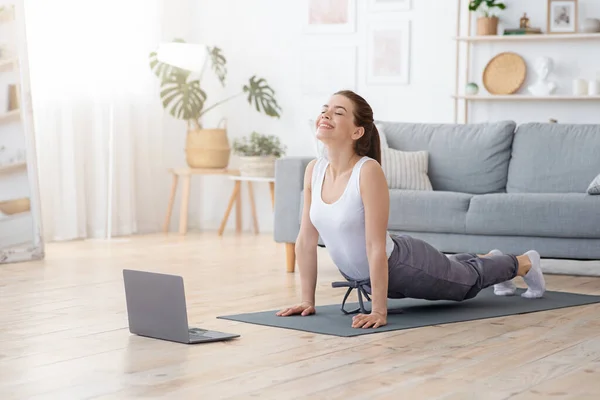 Mujer yoga positiva haciendo práctica de la mañana delante de la computadora portátil —  Fotos de Stock