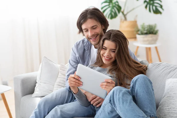 Positivo jovem casal apaixonado usando tablet digital em casa — Fotografia de Stock
