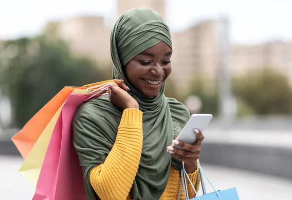 Taxi App. Negro musulmana mujer ordenando cabina al aire libre a través de la aplicación en el teléfono inteligente — Foto de Stock