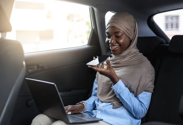 Negro musulmana mujer de negocios grabación audio mensaje con teléfono inteligente en el coche — Foto de Stock